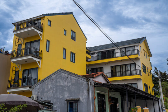 Bright yellow multi-story buildings with black iron balconies beside an older grey structure