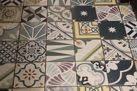 Geometric floor tiles with various patterns installed in outdoor public walkway.