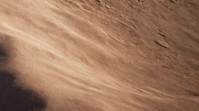 A view of a rough and dry terrain on an alien planet is shown. The sun shines on the rocky landscape. Small rocks and dirt cover the surface. No signs of life are visible.