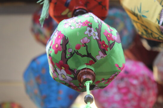 Green fabric lantern with cherry blossom print displayed at a festive craft fair.