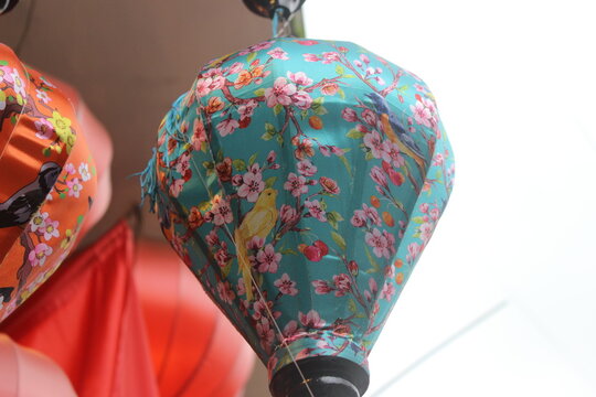 Colorful silk lanterns with floral and bird patterns hanging in local shop front.
