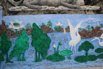 Ornate mural painting depicting blooming lotus flowers and white birds near water. © Stockwise