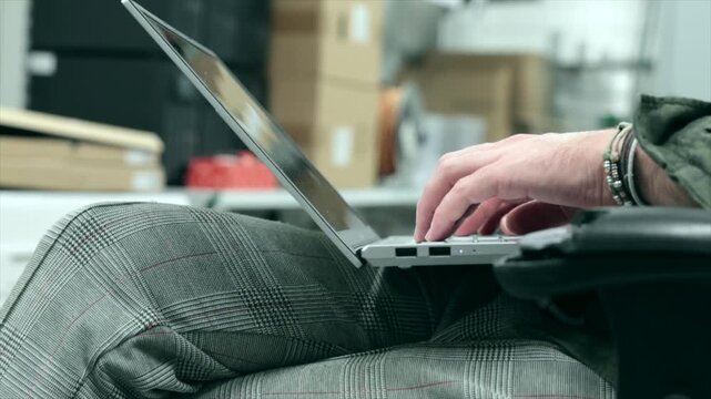 giovane uomo adulto e tecnico informatico esperto lavora e scrive su un computer portatile all'interno di un ambiente industriale
