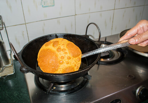 Indian cooking activity that is frying puring in Kitchen. 