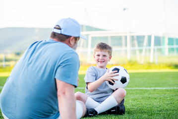 Naklejka premium Dad and son having fun while practicing football outdoors.
