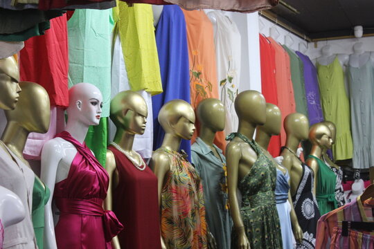 Display of colorful summer dresses on gold mannequins inside a clothing retailer.