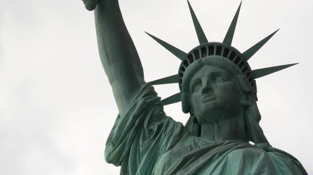 Statue of Liberty on Liberty Island, New York, United States. Blue cooper monument, symbol of democracy and patriotism near Manhattan, NYC USA. Clouds on sky. American independence. Torch and crown.