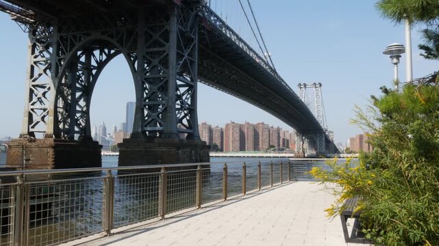 Williamsburg Bridge in Brooklyn, New York City, United States. Transport metallic bridge over East River water near Marcy Av subway station and Domino park in Williamsburg. Riverfront summer promenade