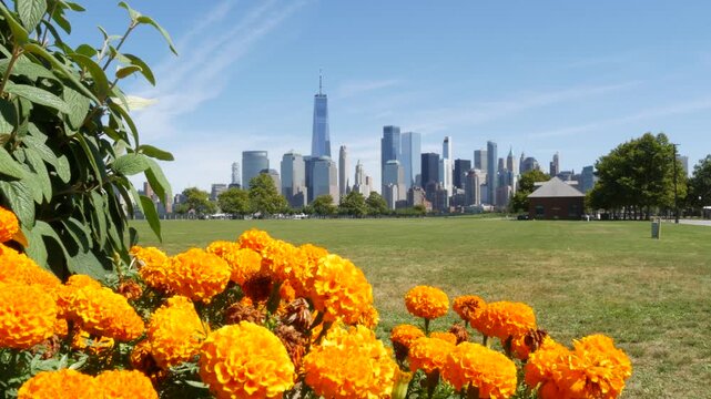 New York City Manhattan Downtown Financial District skyline, World Trade Center tower from New Jersey Liberty state park, United States. Green grass lawn, flowers and skyscraper buildings cityscape.
