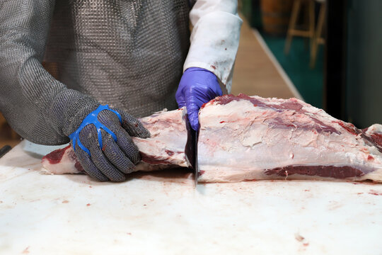 profesional de la industria c&aacute;rnica, partiendo carne de cuerpo de vacuno con guantes de malla