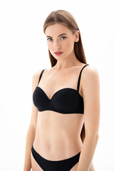 Naklejka premium Young charming woman in black lingerie posing on a white Isolated background