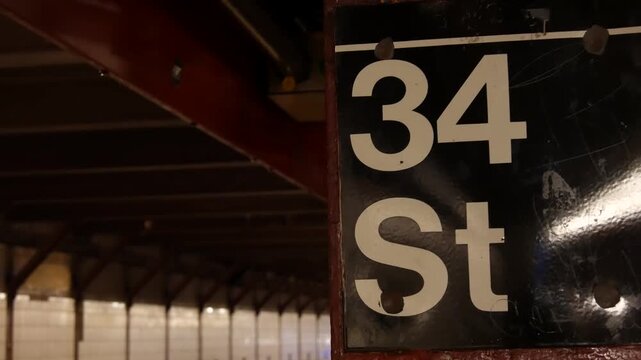 New York City Manhattan Midtown subway platform, 34 street metro near Herald Square and Penn Station, United States railway. Public metropolitan transport in USA, american railroad. Sign on column.