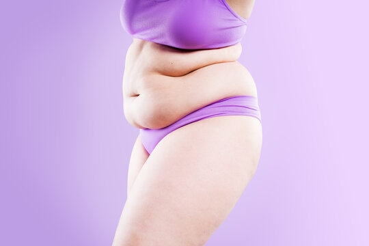 Overweight woman with belly fat in underwear on purple background. Obesity, weight loss, diet and body positivity concept