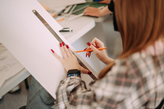 Architectural student drawing blueprint with ruler during design class