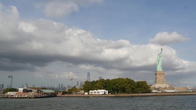 Statue of Liberty on Liberty Island, New York, United States. Cooper monument, symbol of democracy and patriotism near Manhattan, NYC USA. View from river ferry boat, tourist cruise. Cityscape skyline