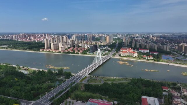 Aerial view of Rizhao city with river and cable-stayed bridge under clear summer sky