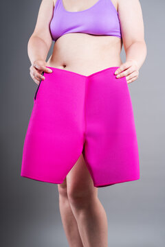 Overweight woman holding pink neoprene slimming shorts. Weight loss, and body shaping concept