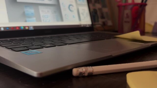 Hand removing adhesive sticky note from laptop computer during business data analysis in office workplace, concept of completing a task and finishing work
