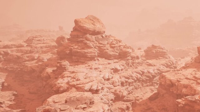 Strong winds blow dust across a rocky landscape. The brown and orange hues mix under a hazy sky. The ground shows layers of sediment from erosion over time.