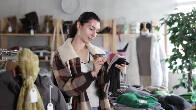 Armenian woman stands in a store and chooses warm gloves for autumn and winter, she looks at which ones will suit her coat and jacket. High quality 4k footage