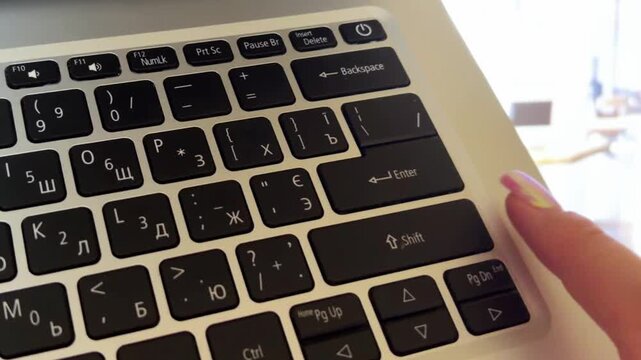 Woman's hands with pink manicure typing on laptop keyboard, office worker pressing enter key to send message or finish work, concept of business and communication