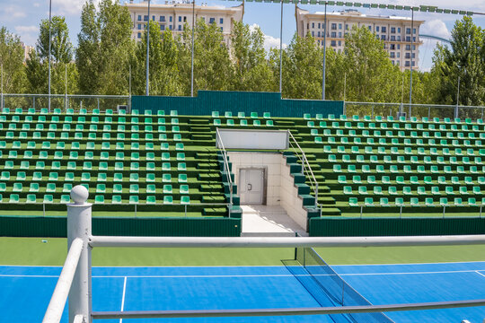 Outdoor Tennis Stadium with Empty Green Grandstand Under Blue Sky. Sports venue ready for training tournaments and public events.