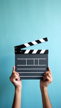 Hands hold a film clapperboard ready to start filming. This movie production tool is used for scene identification and synchronization. Pro cinema slate signals movie scene beginning.