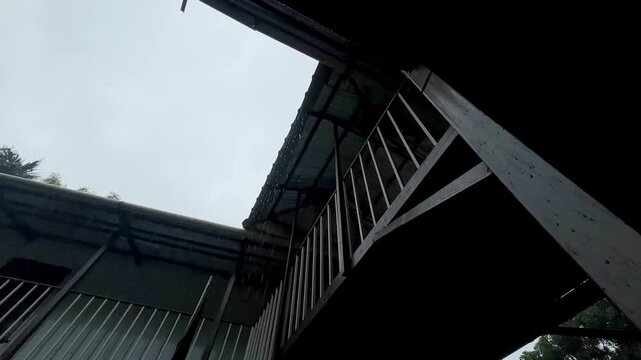 Dark Cinematic Architecture: Low Angle View of Rainwater Dripping off a Balcony