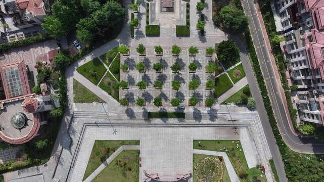 Aerial view of an urban plaza with geometric paving patterns green trees and landscaped gardens