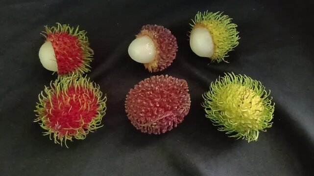 A group of three pulasan fruits (Nephelium mutabile) , Yellow rambutan or Nephelium lappaceum (yellow cultivar) and Red rambutan or bNephelium lappaceum ripening stages, with partially opened fruits r