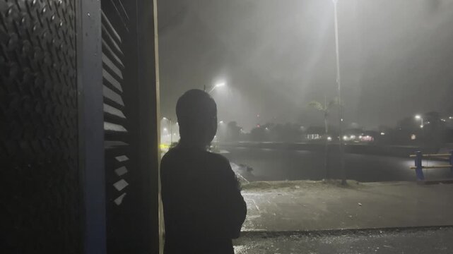 Man standing in the rain at night