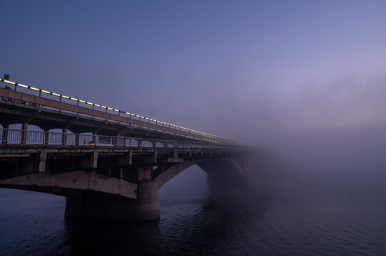 Morning cityscape with old bridge ang fog over river