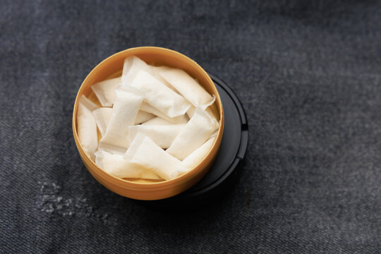 Snus pouches in a yellow container placed on a dark surface