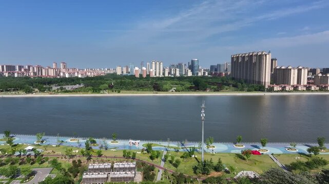 Rizhao city riverside park with green spaces and modern high-rise skyline under clear blue sky