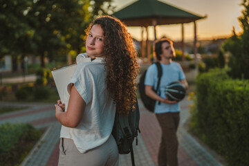 Fototapeta premium Female student looking back with male friend walking behind