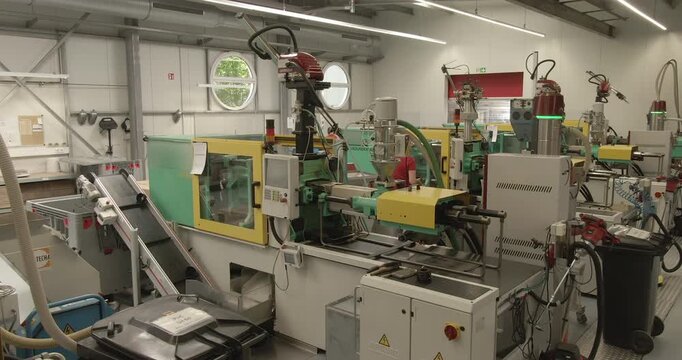 Industrial factory interior with multiple injection molding machines in operation on a production floor
