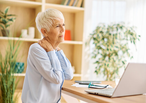 Portrait of a mature senior woman a businesswoman working on laptop  from home having a meeting online having a headache or being stressed, home office, or a student learning, or mature woman surfing 