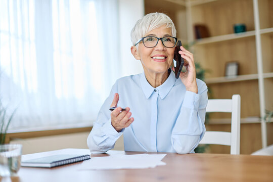 Portrait of a mature senior woman or a  businesswoman working from home having a meeting online, home office, or a student learning, or mature woman having a phone call, holding a mobile phone, smartp