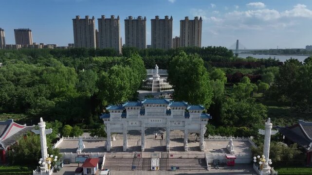 Rizhao city park with lush green trees and modern high-rise buildings in the background