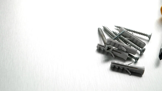 Assorted screws and plastic wall plugs on a brushed metal background
