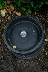 Black plastic-encased commercial beer keg left outdoors, featuring a black top and base with a central stainless steel valve connector. Commonly used by pubs, breweries, bars, and hospitality venues © Val