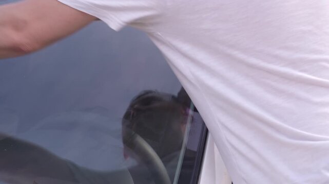 A man applies a ceramic anti-rain coating to the windows and headlights of a car.