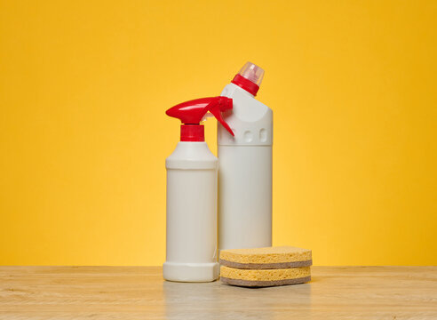 White plastic spray bottle wooden surface against a yellow background.