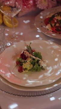 Vertical video. Waiter serving fresh salad onto guest plate during wedding banquet at restaurant.