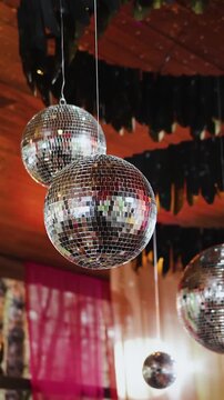 Vertical video. Wedding venue ceiling decorated with spinning mirror disco balls.