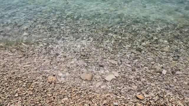 Waves on pebbles beach at Garda Lake, Bardolino, Italy. Wave moving top to down frame.