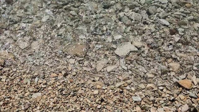 Waves on pebbles beach at Garda Lake, Bardolino, Italy. Wave moving up to down frame.
