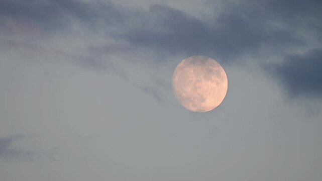 Moon at dusk illuminated clouds, movement at slow pace, close up, vivid background authentic video. Setting sun illuminated clouds