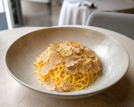  Delicados Tagliolini al tartufo bianco servidos con una cremosa salsa de mantequilla y queso, cubiertos con finas l&aacute;minas de trufa blanca fresca en un elegante restaurante de alta cocina.