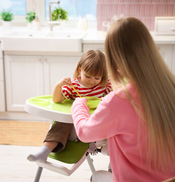 Work for teenagers. Teen nanny feeding cute baby on chair at home